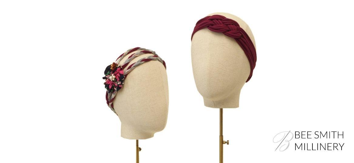 Two head mannequins model upcycled headbands made by Bee Smith. One is sark read, the other is multicoloured and features a fabric flower.