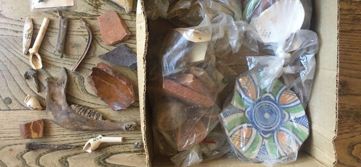 An box full of old archaeological finds including broken pieces of pottery