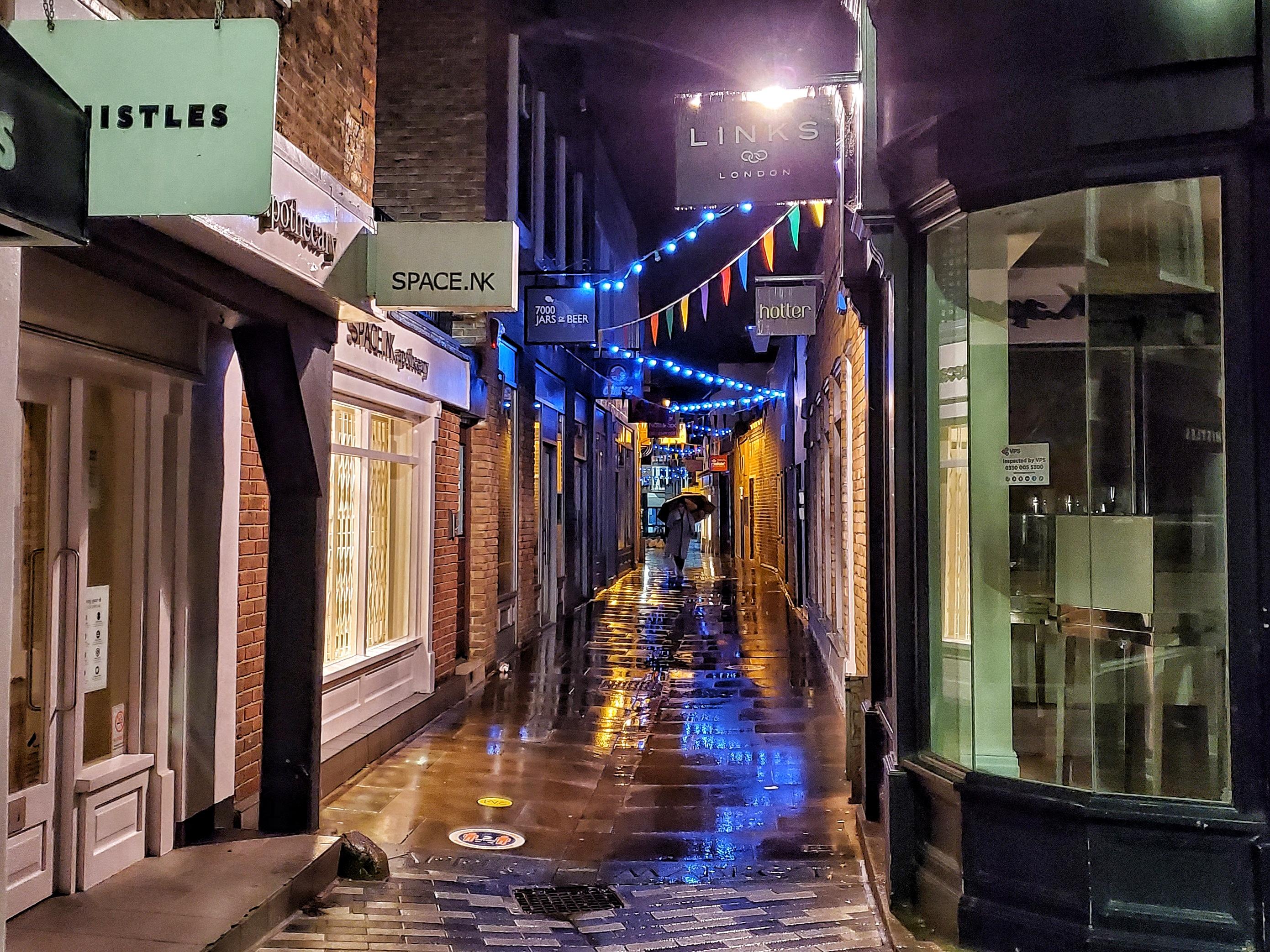 A rainy and empty Crown Passage leading away from Kingston Market place with closed shops.