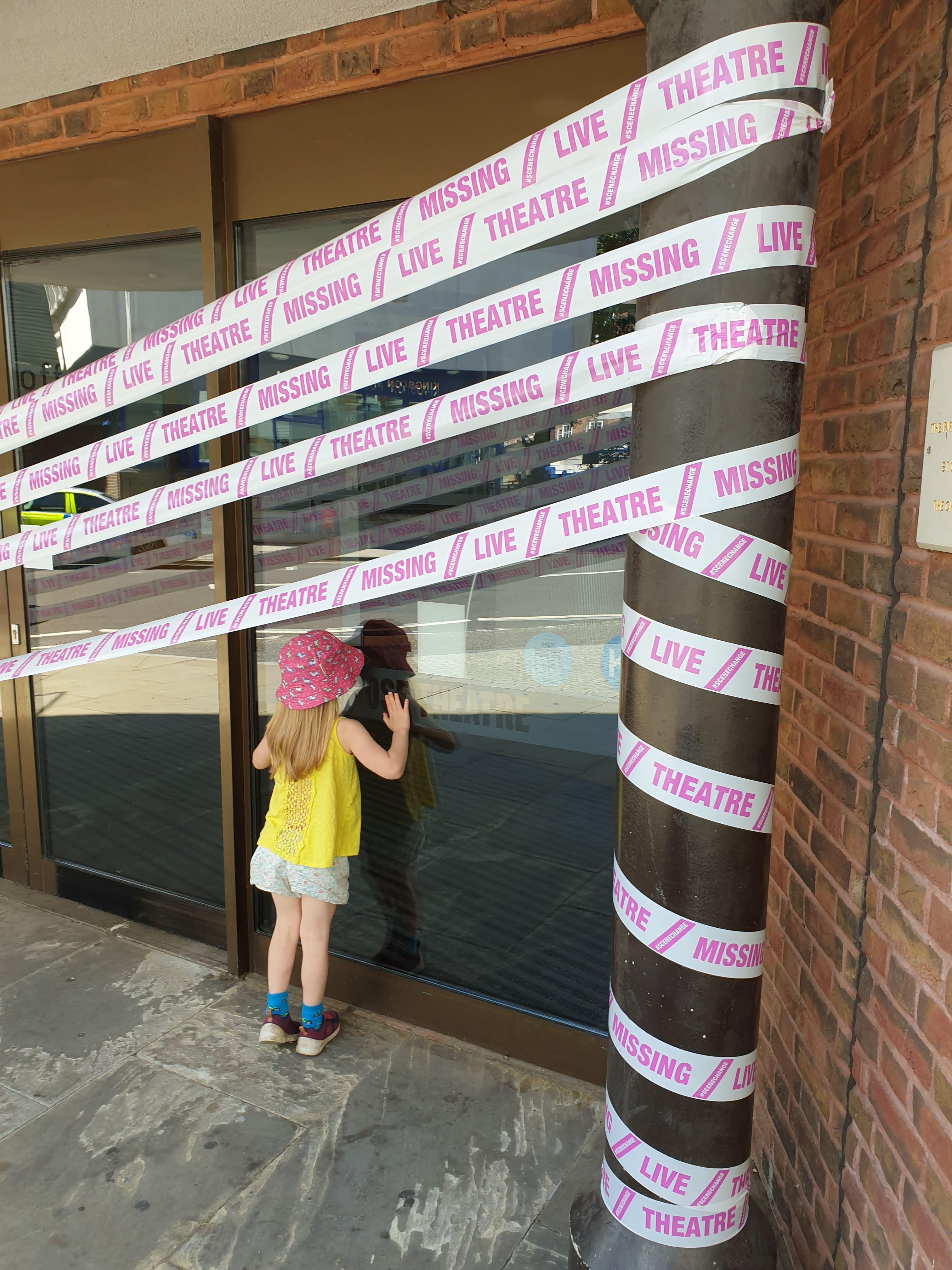 A young girl peers in through a window of the closed Rose Theatre. The window is covered with police style closure tape as part of the &#039;Missing Theatre&#039; campaign.