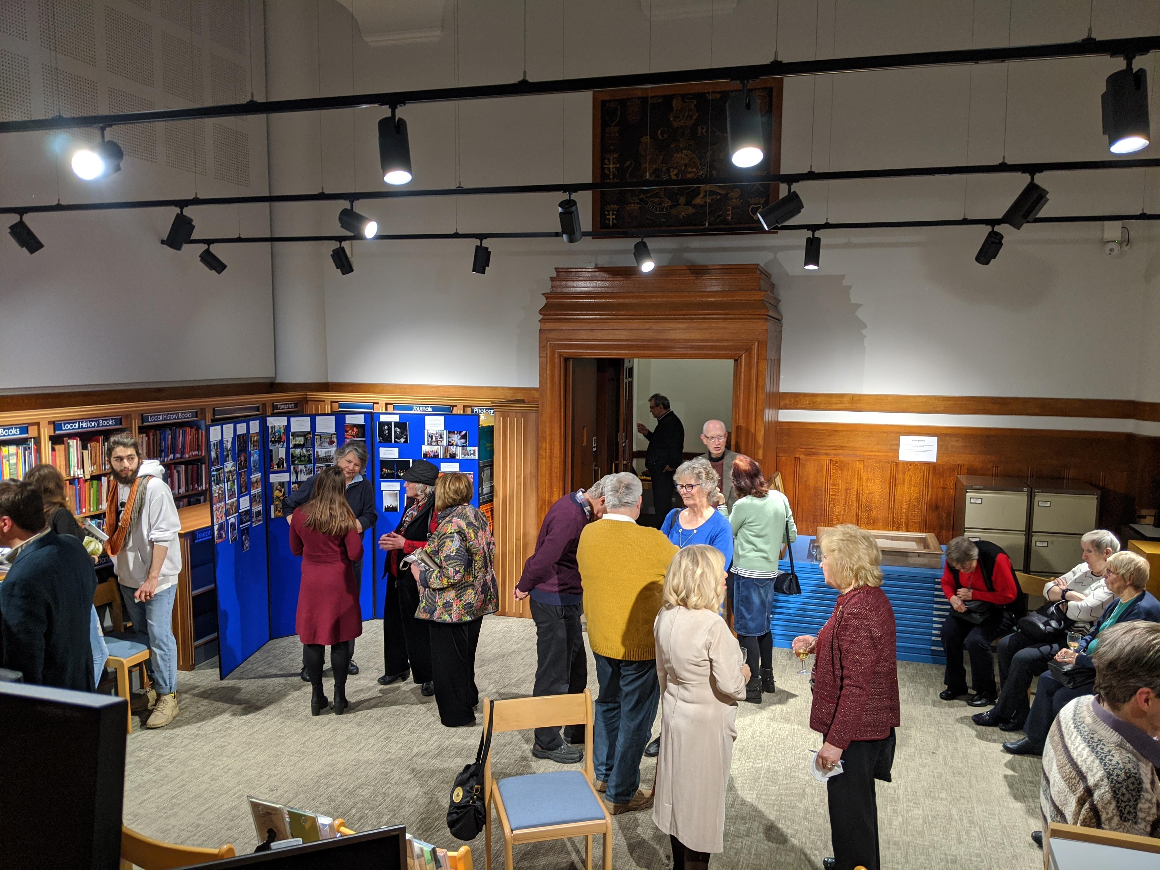 People milling around a museum exhibition. Talking and looking at exhibits