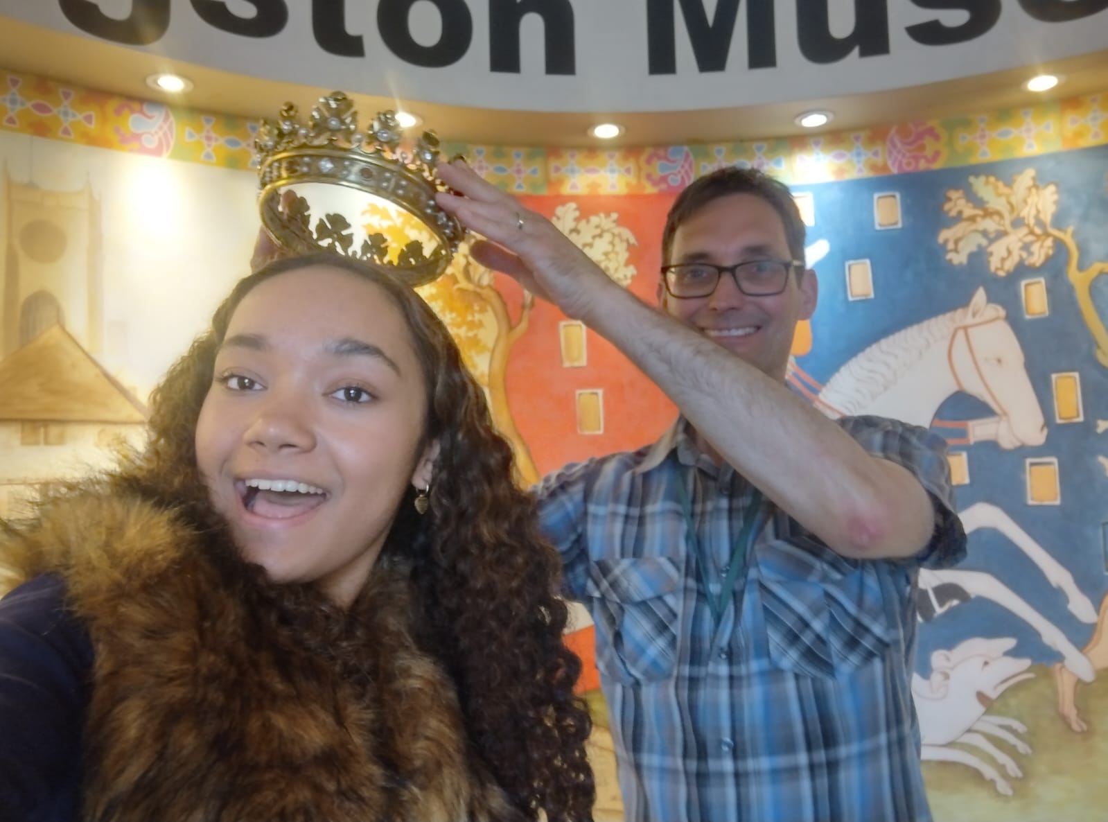 Image of a man putting a crown on a women's head as she smiles for the camera.
