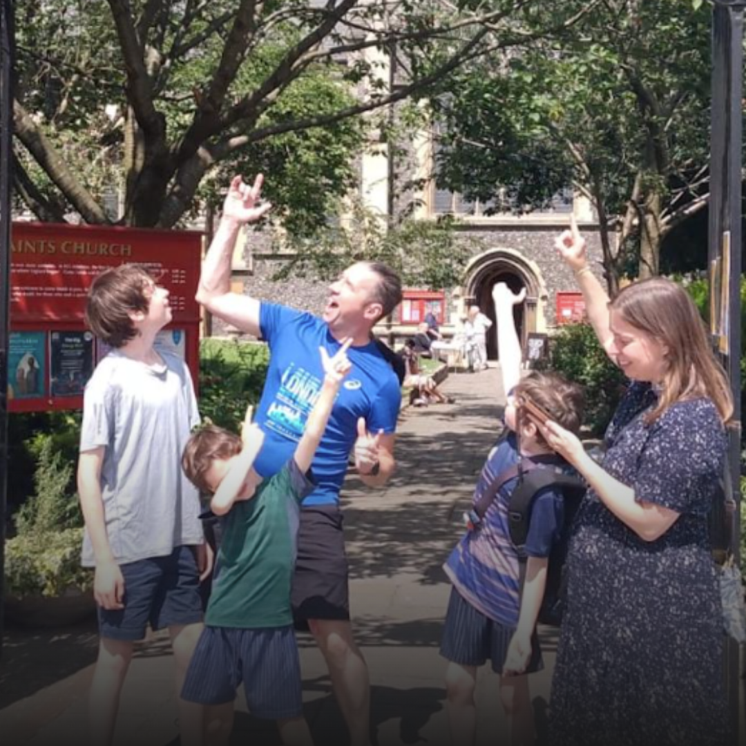 Family of 5 outside a church pointing to the sky on the treasure hunt. 