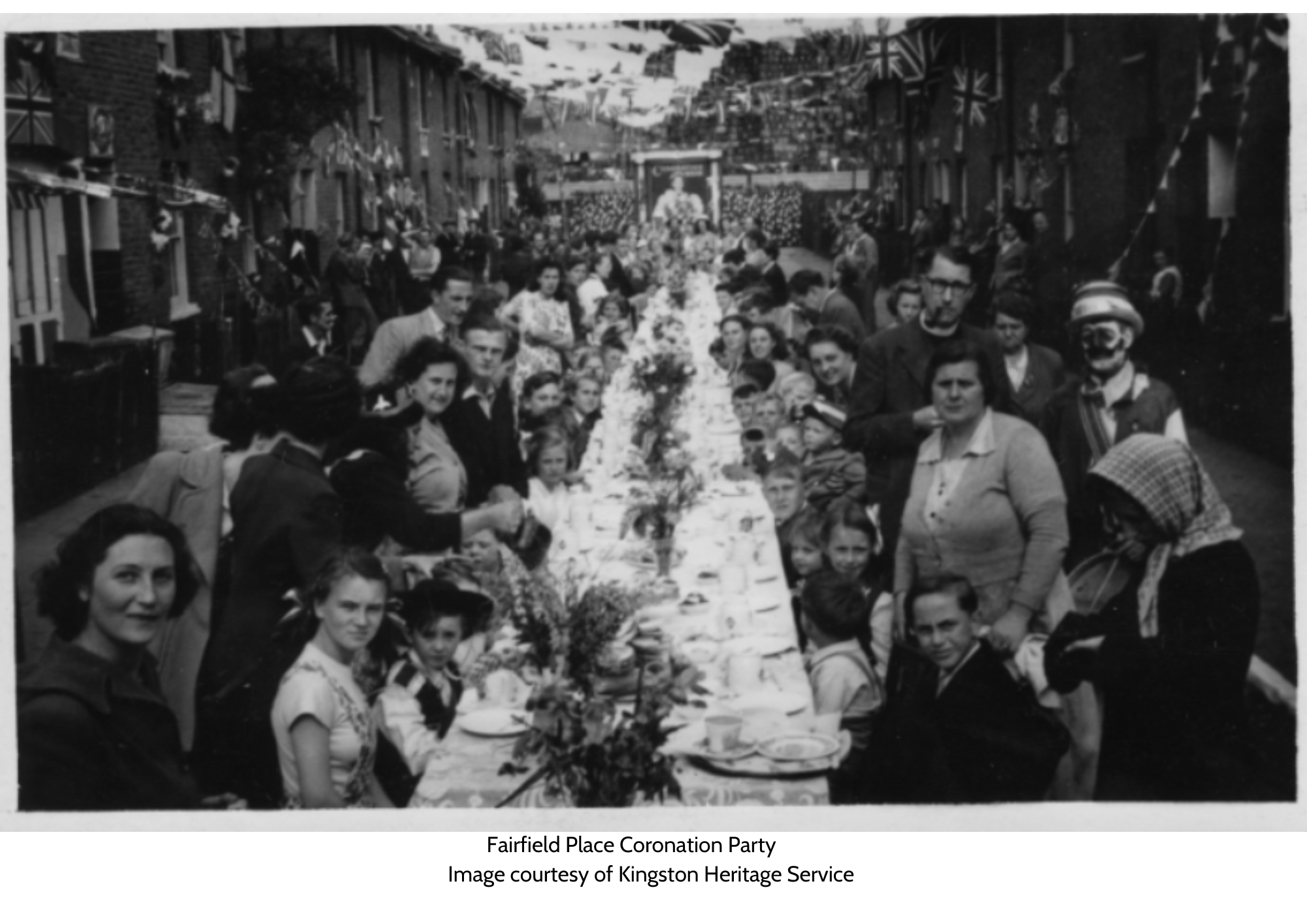 Old black and white image of Fairfield place coronation party. One long table with people on either side looking at the camera