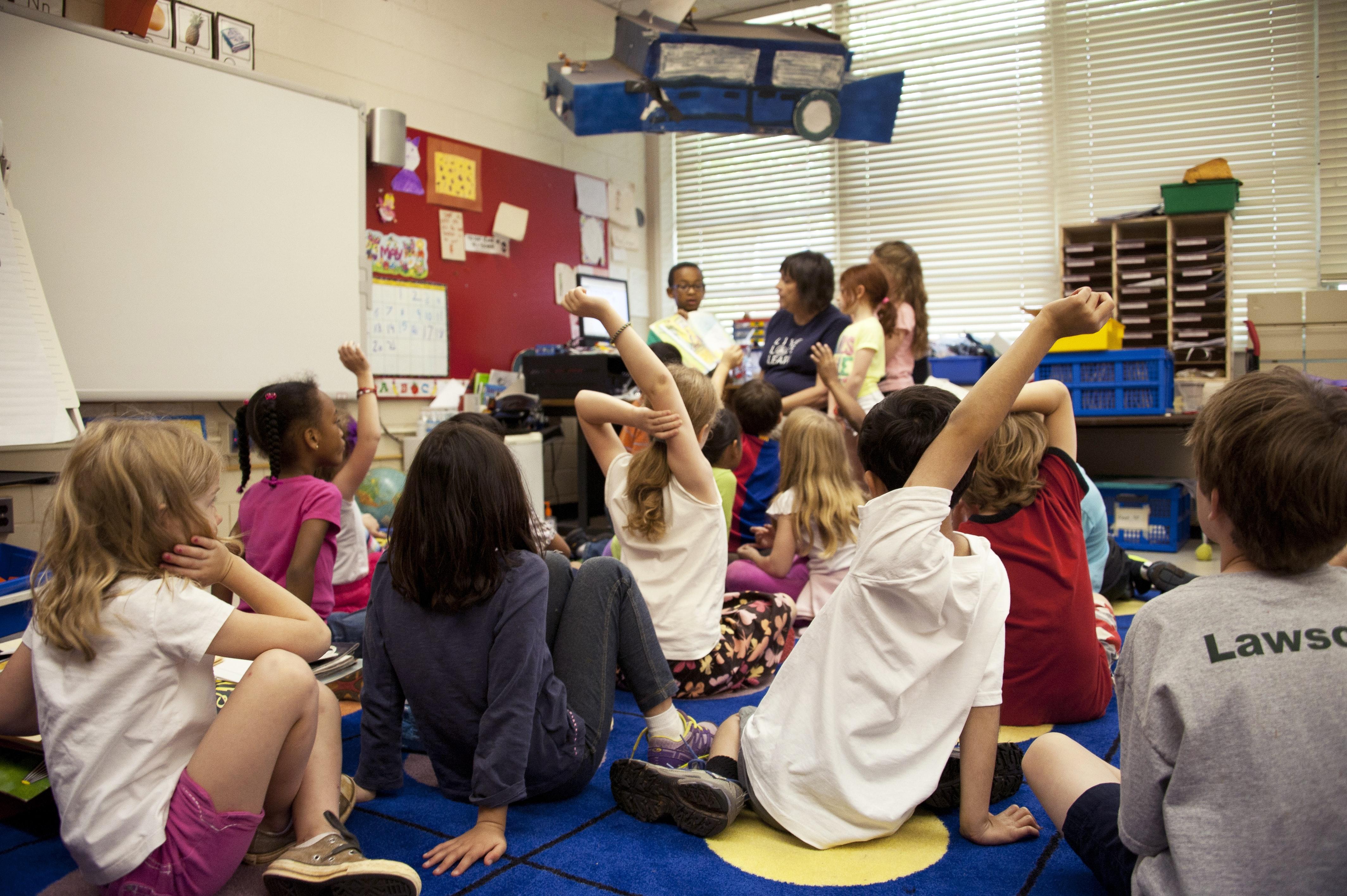 A group of children sat on the floor in a school classroom