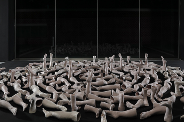 lots of white mannequin legs on the floor in a black space