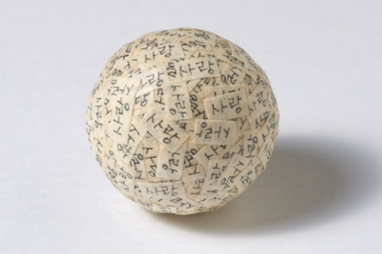 Lots of small pieces of rectangular paper stuck together to form a ball 